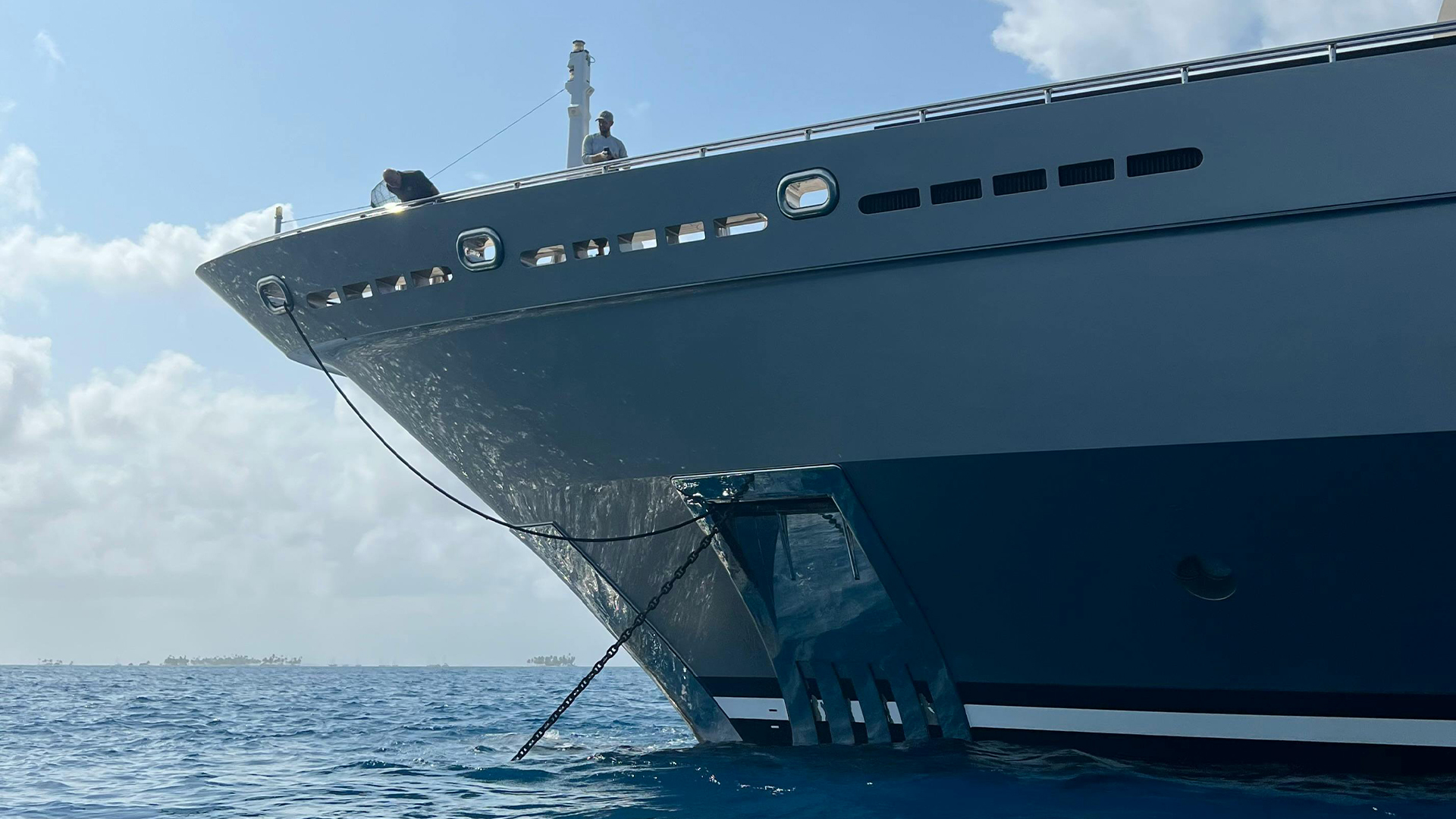 The bow of an anchored superyacht in calm water