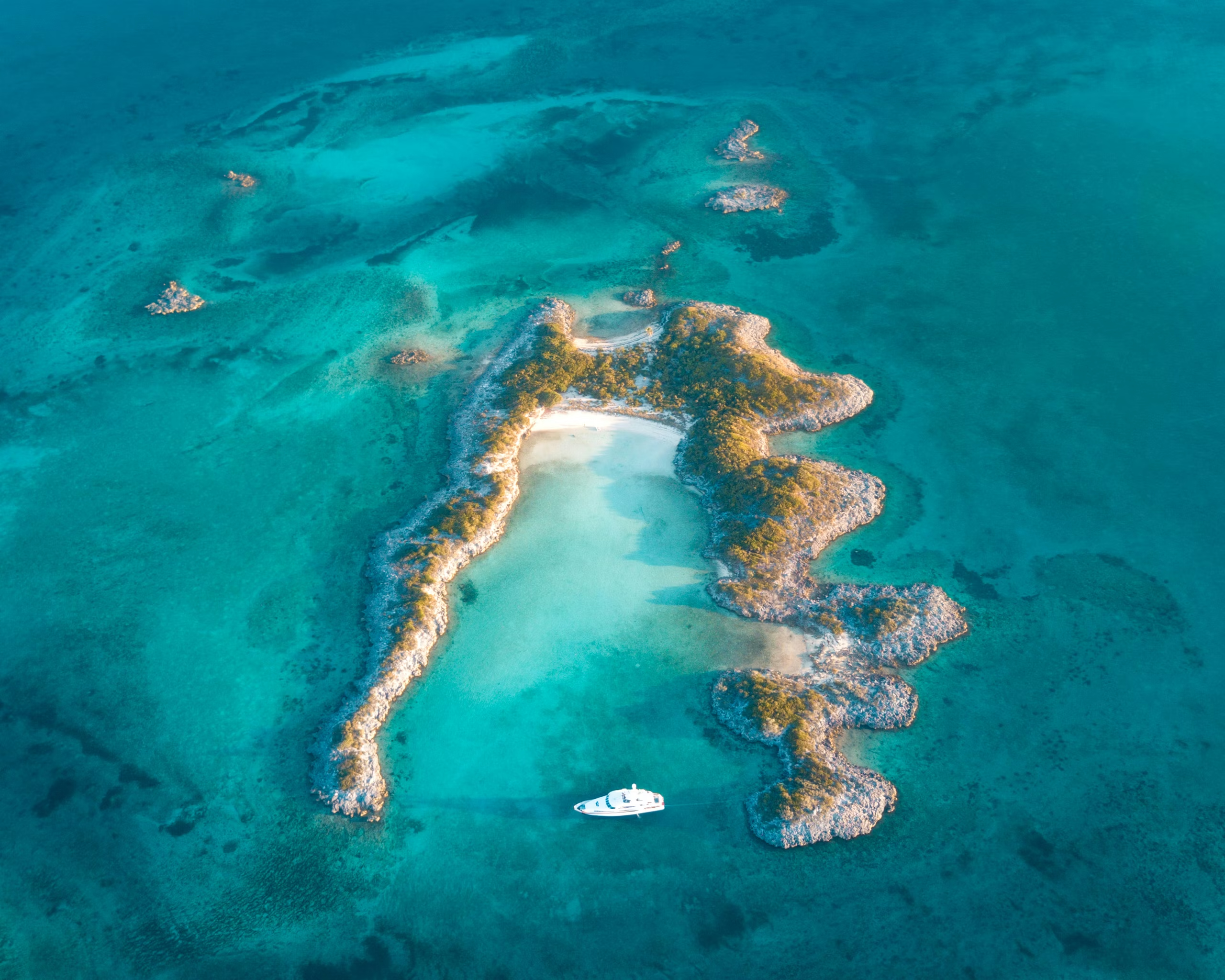 Vista aérea de un yate fondeado en aguas turquesas rodeado de bancos de arena