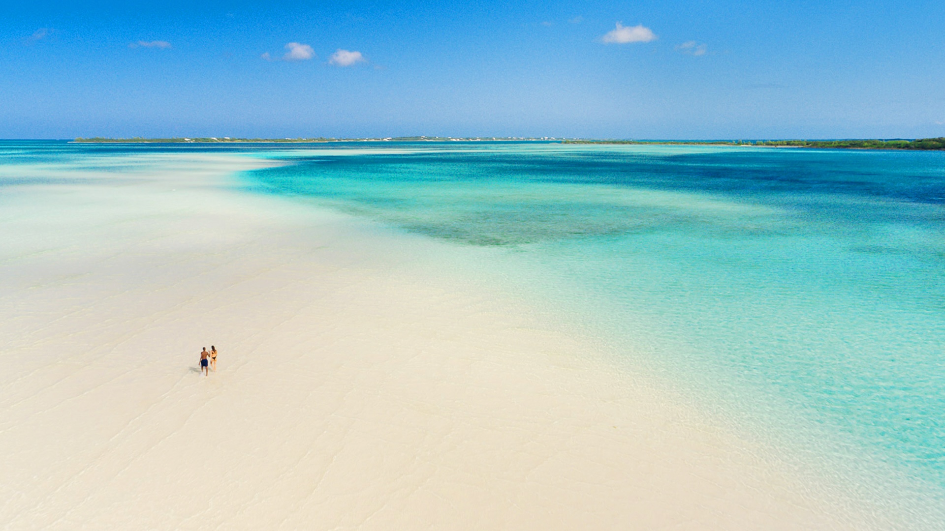 Aerial view of a long sandbar reaching into shallow Bahamian water
