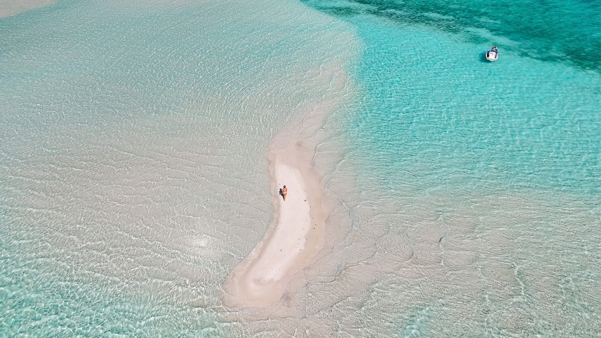 Vista aérea de un banco de arena en marea baja con una pequeña figura caminando