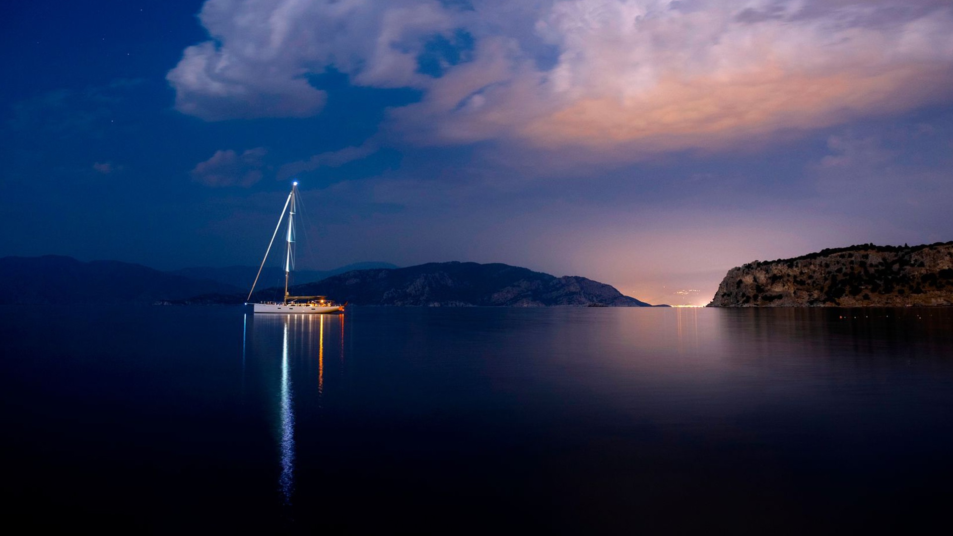 A sailboat at anchor in a bay at dusk