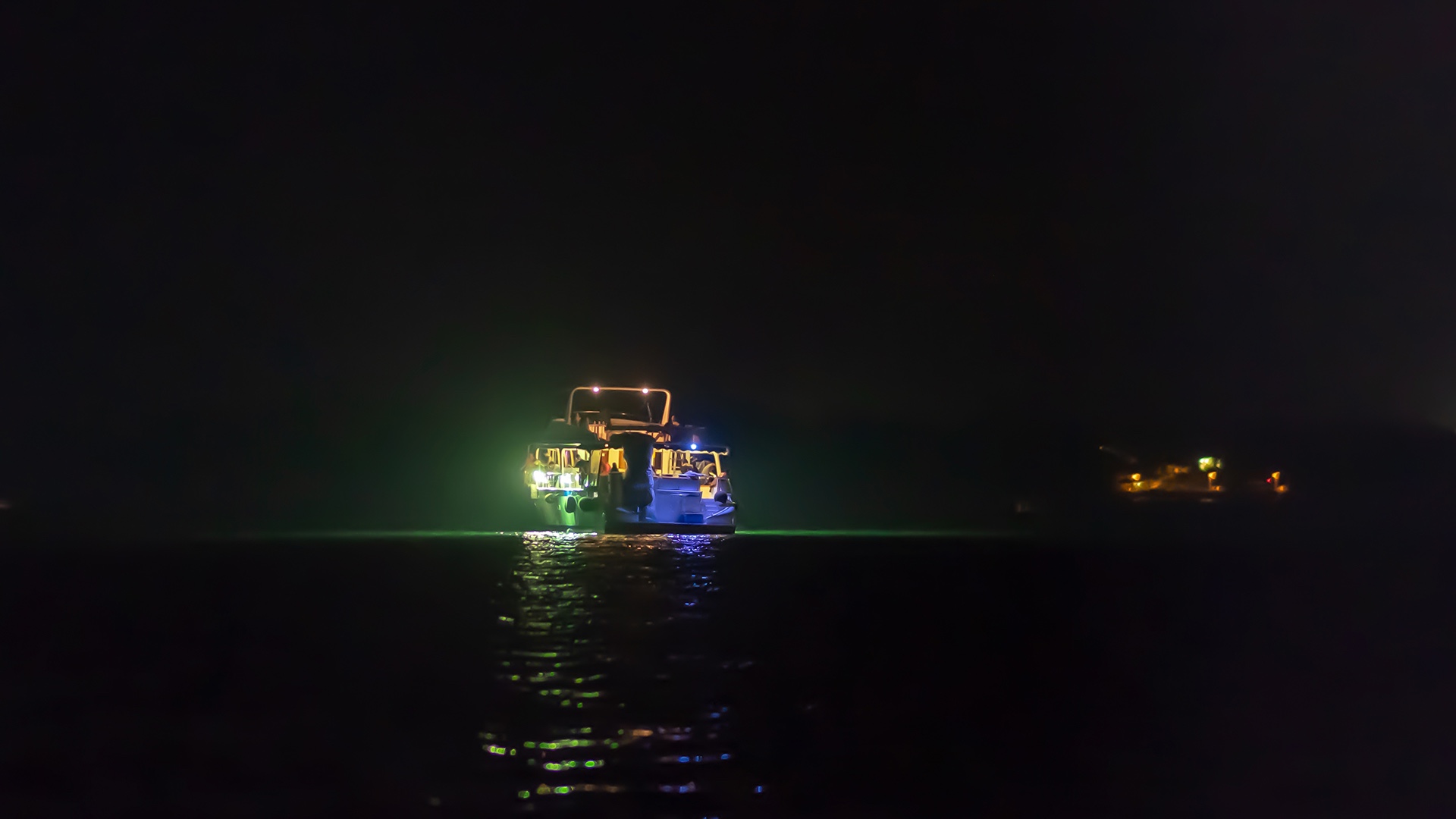 View from the stern of a boat heading out into the ocean at night