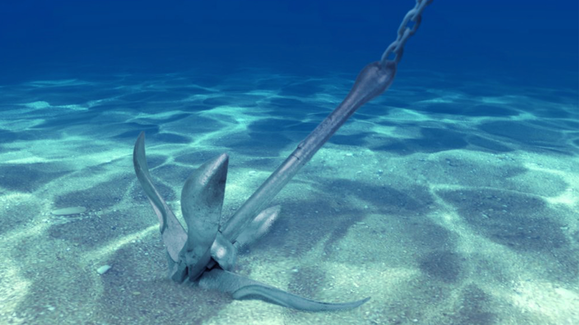 Anchor buried in white sand under transparent water