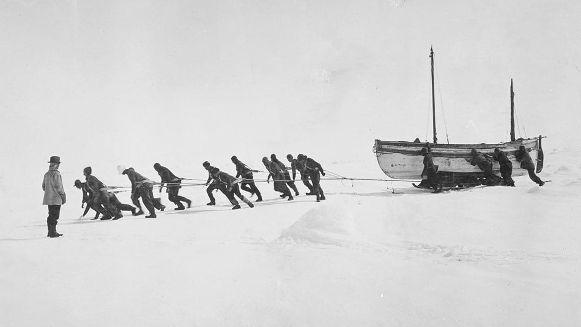 Crew members pulling on ropes to drag one of the lifeboats across the ice