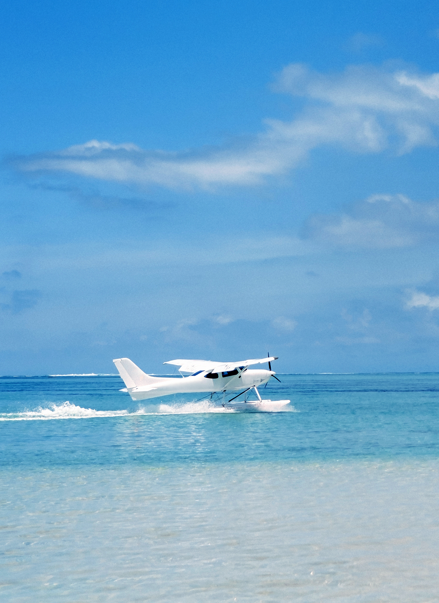Seaplane touching down on turquoise Bahamian water, vertical composition