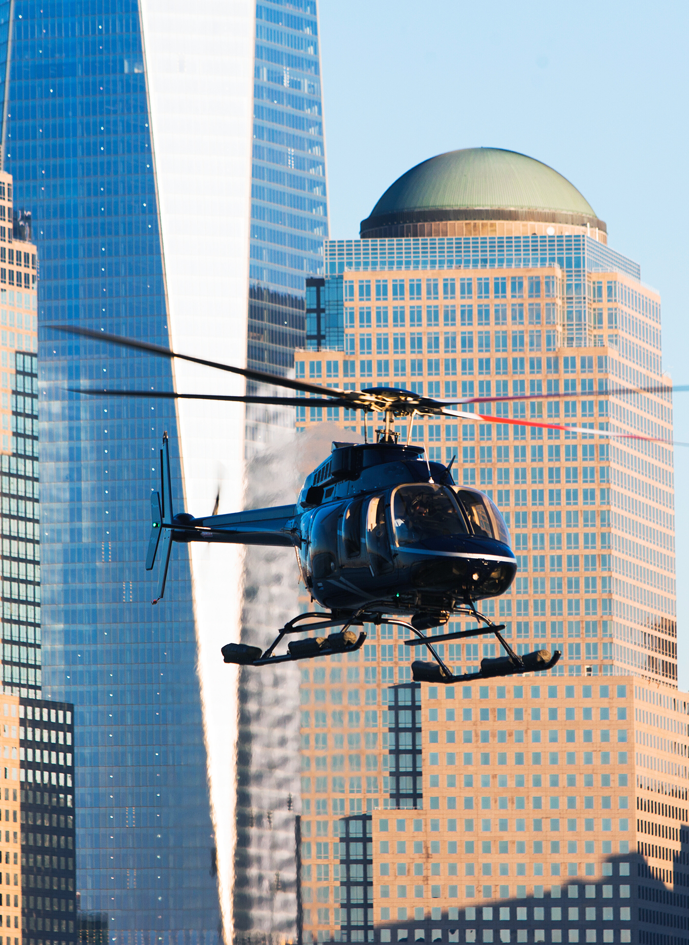 Helicopter flying above city skyscrapers in daylight