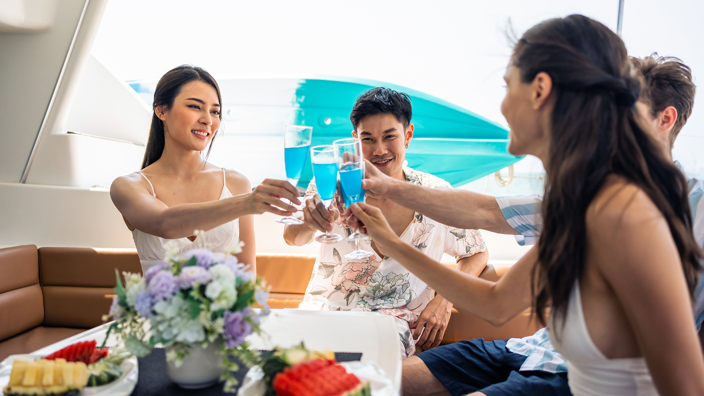 Dos parejas tomando champ&aacute;n con fruta en el cockpit de un yate