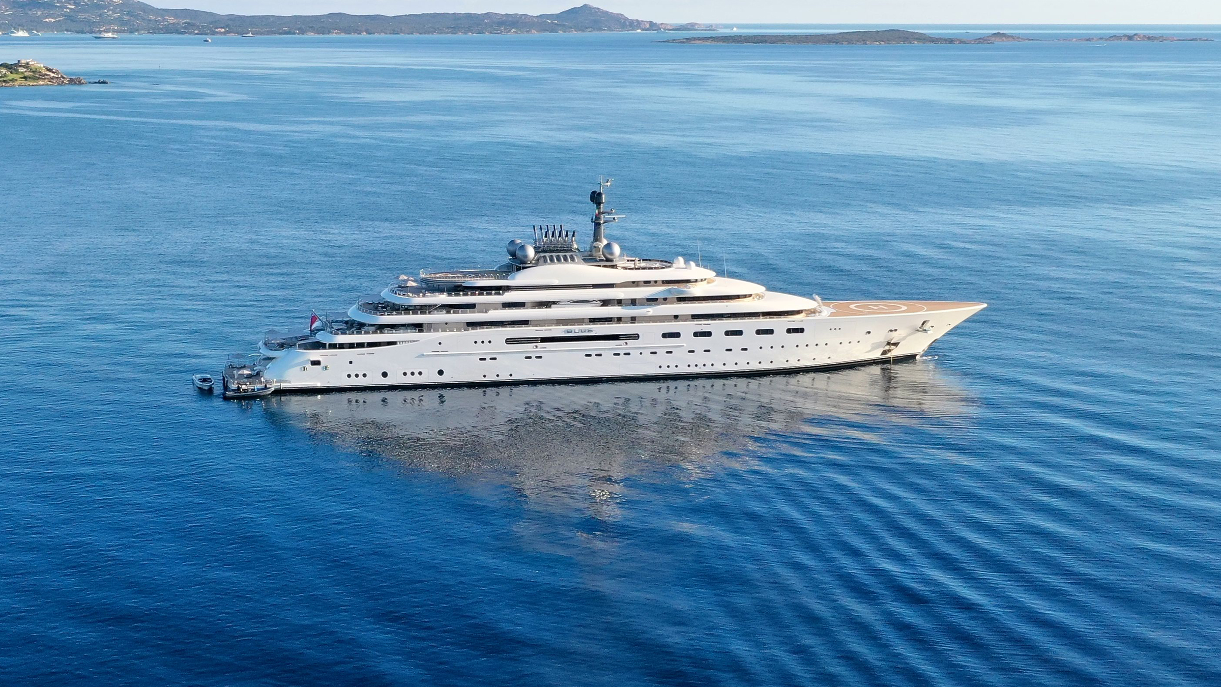 Large yacht with a forward helideck at anchor in a calm bay