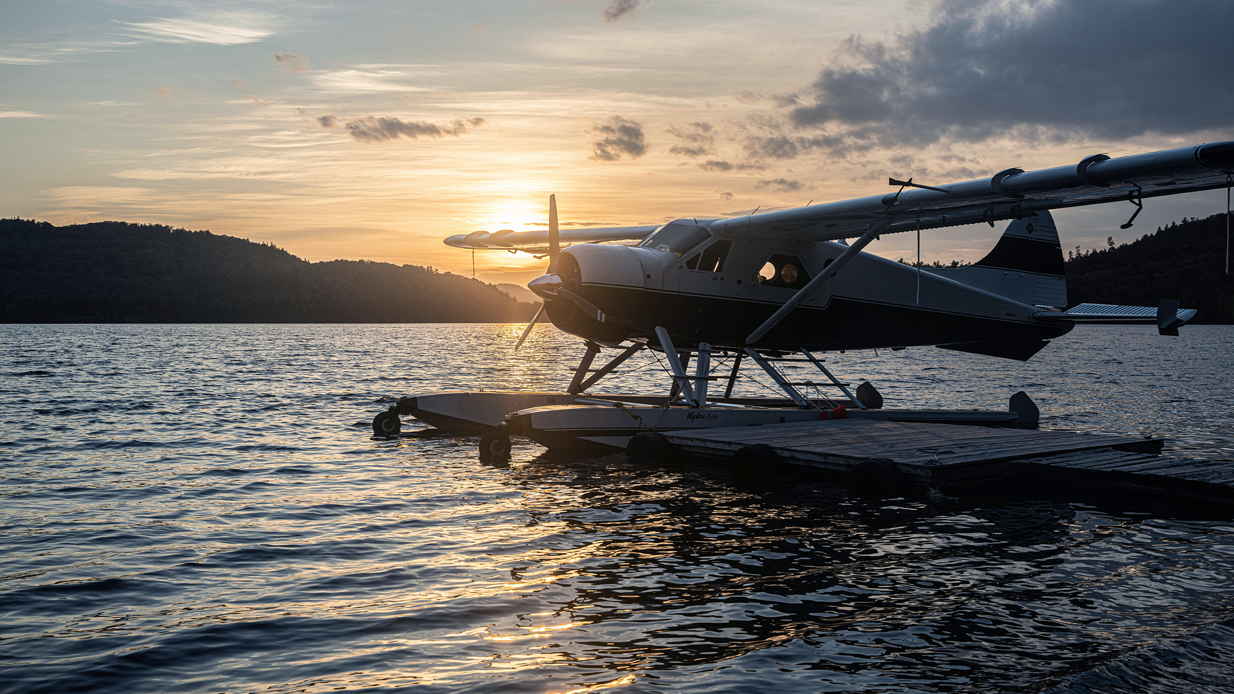 Seaplane moored to a dock, backlit at dusk