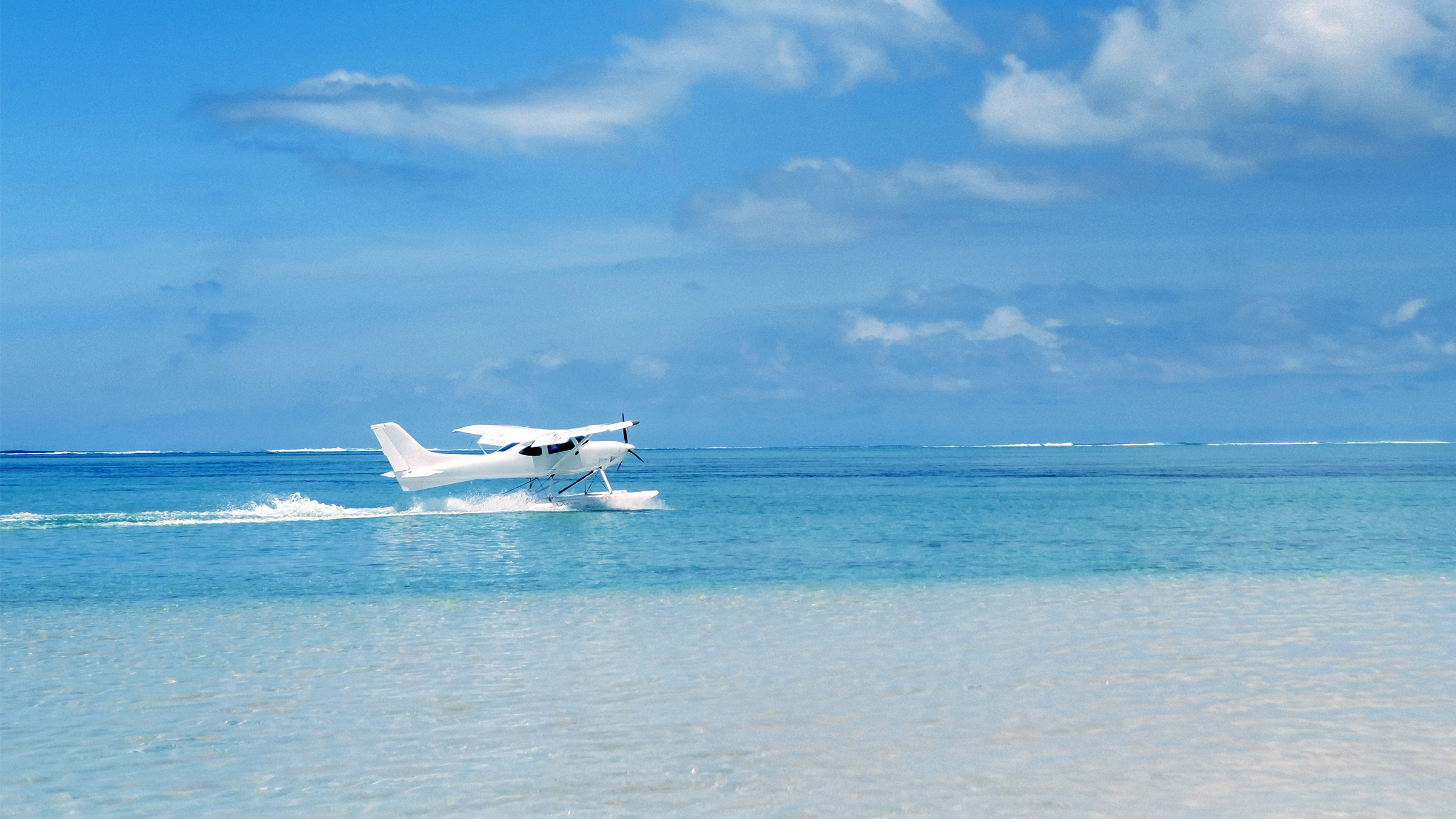 Seaplane touching down on turquoise Bahamian water