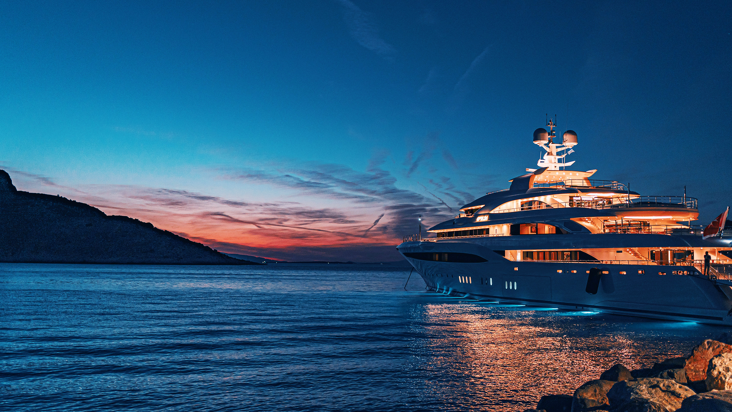 Yacht anchored at sunset beside a rocky coast