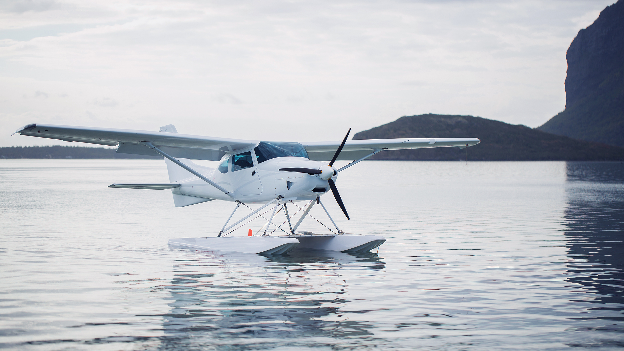 Seaplane low over the water near a mountainous coast