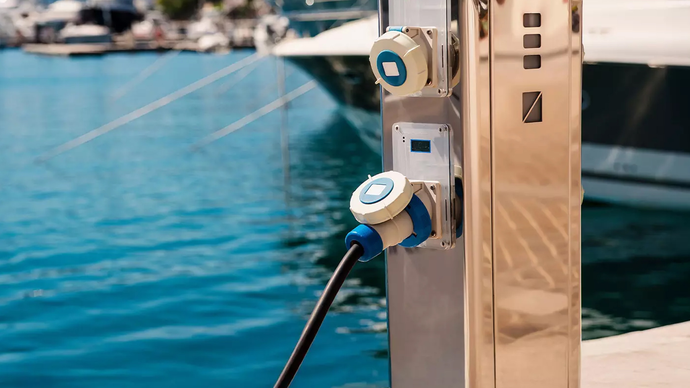 A shore power and water pedestal with boats behind