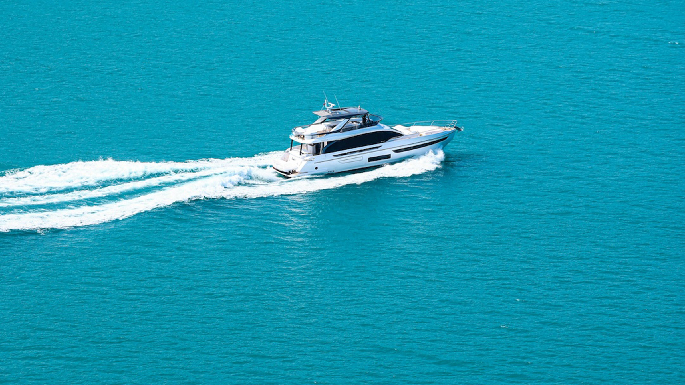 Vista aérea de un yate cruzando hacia las Bahamas sobre aguas turquesas
